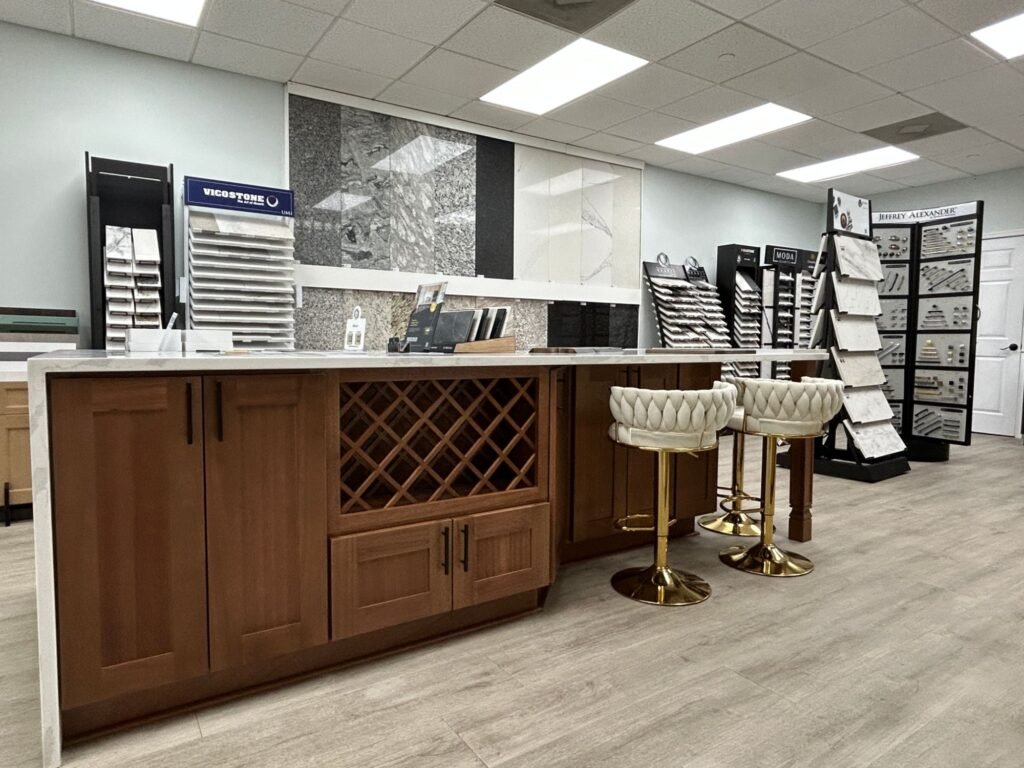 Quartz and granite countertop sample racks behind a wood display island at Land of Cabinets