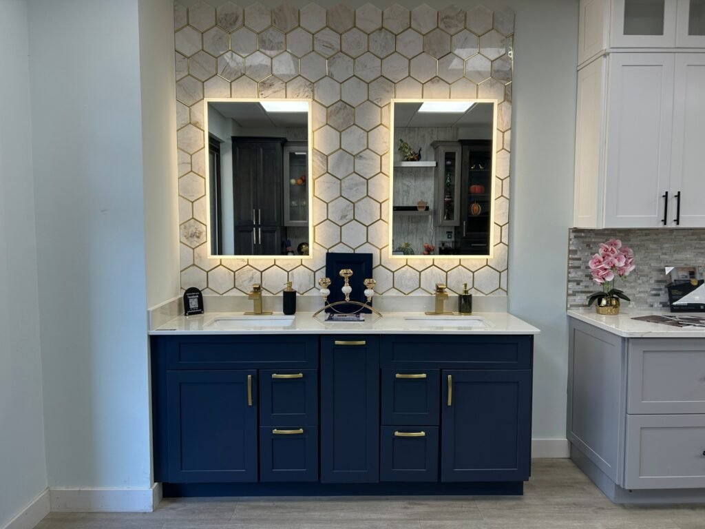 Navy double bathroom vanity with lit mirrors and a white hexagon tile backsplash on the showroom floor